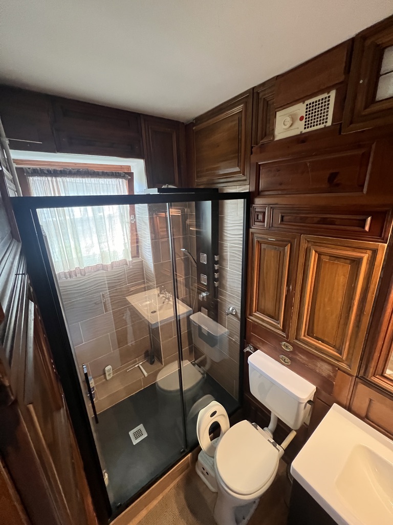 Bathroom with glass shower cabin and wooden cabinets