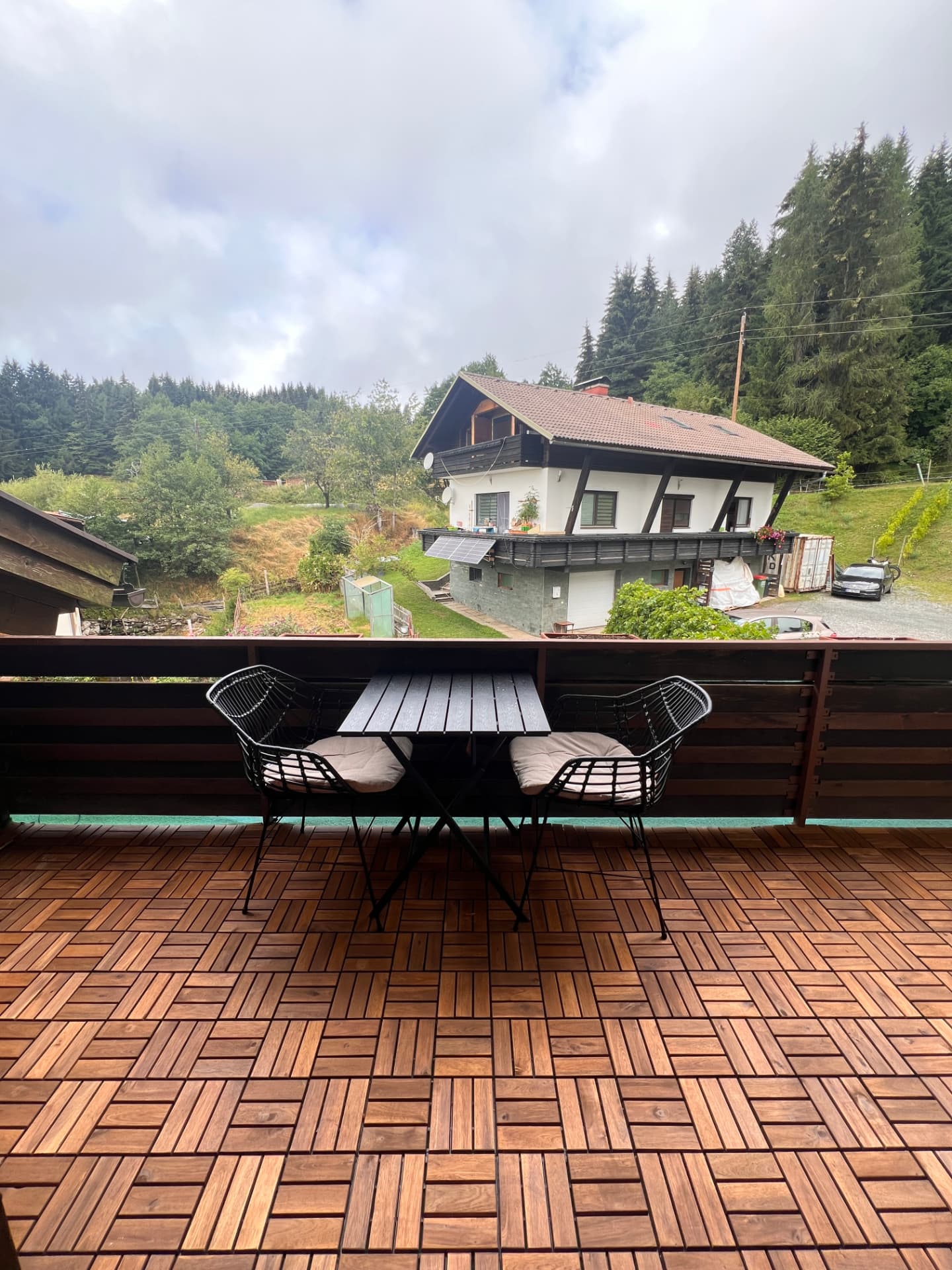 Balcony with table and chairs looking towards forested hills