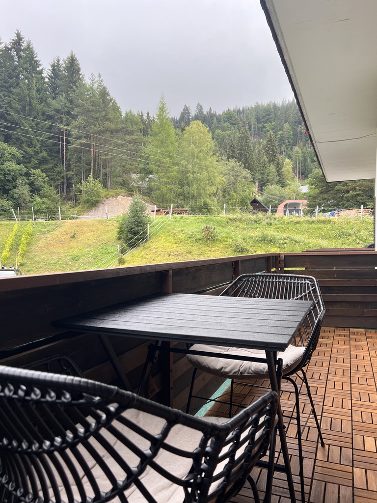 Balcony table and chairs facing the forested hillside on a misty morning