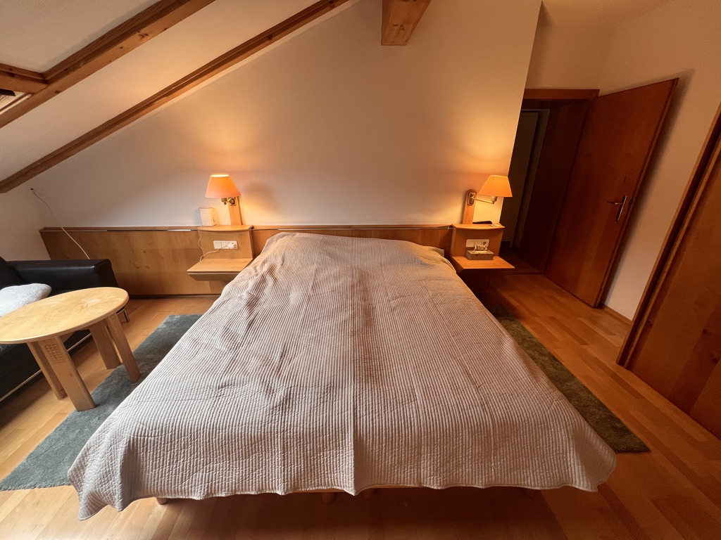 Double bed with bedside lamps under the sloped attic ceiling