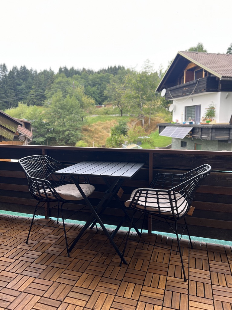Balcony bistro set on wooden decking with view of alpine chalets